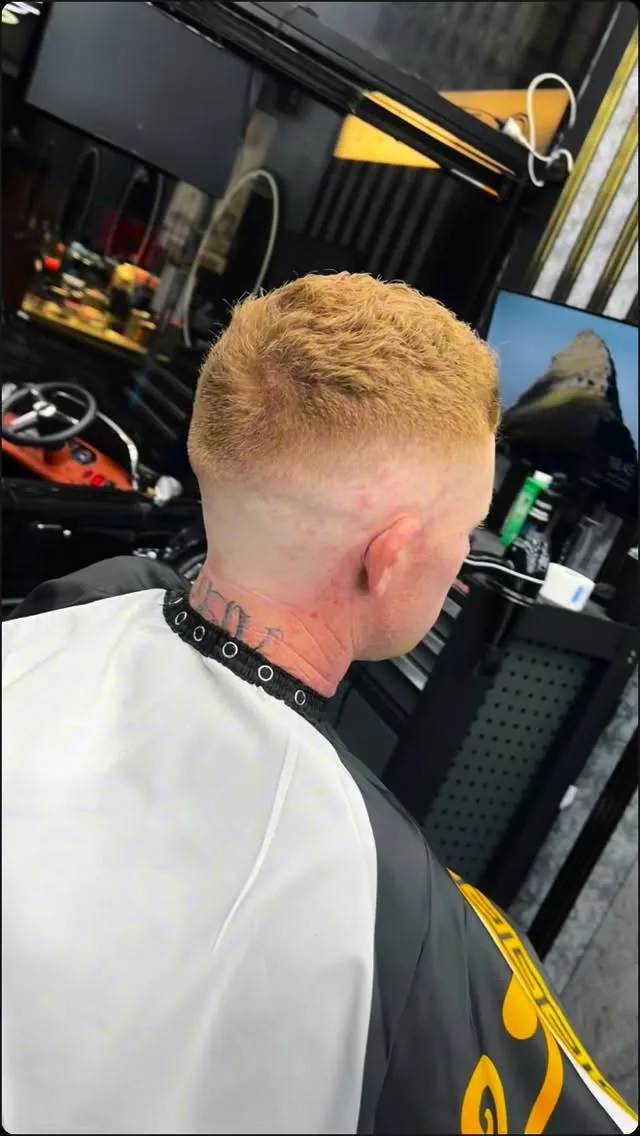 Black spiky mullet and taper, red pinstripe cape, hexagon LED ceiling behind.