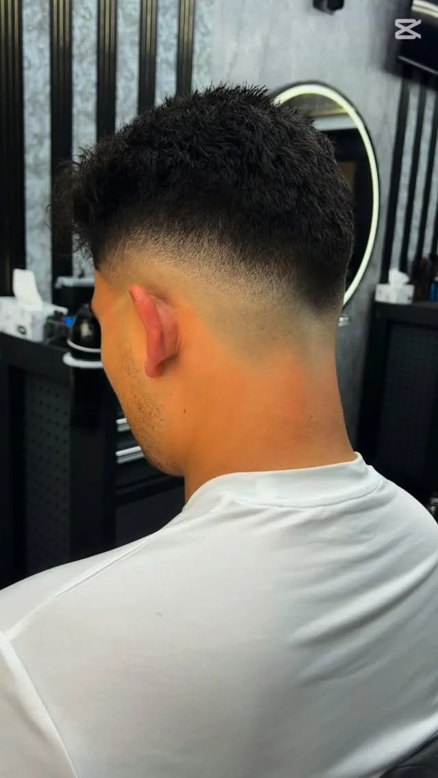 Side profile, black textured mullet and quiff, red pinstripe cape, hexagon ceiling and arch mirror.